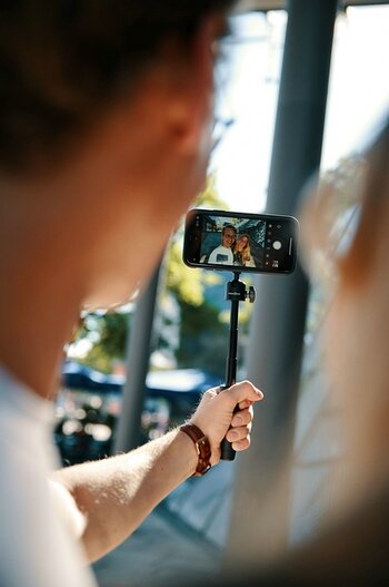 Blick ueber die Schulter: Paerchen macht Selfie mit Smartphone auf VACUUM mini triopod von FIDLOCK
