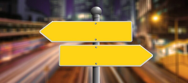 Symbolbild für Entscheidung: Zwei gelbe Wegweiser zeigen nach links bzw. rechts