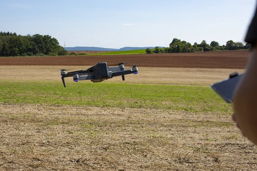 GPS-Drohne QC-120 GPS von Maginon in der Luft über einem Feld