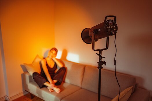 Anwendungsbeispiel: Dauerlicht Soluna 150 RGB von Rollei leuchtet Sofa mit Model aus