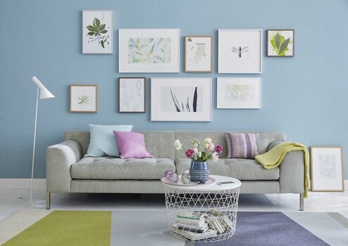 Wandhaengung ueber Sofa - helle Motive auf blauer Wand