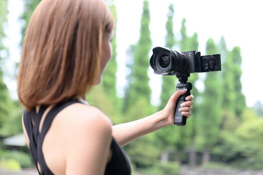 Frau fotografiert sich selbst mit 20-40mm F/2.8 Di III VXD für Sony E-Mount an Sony Kamera mit Handgriff