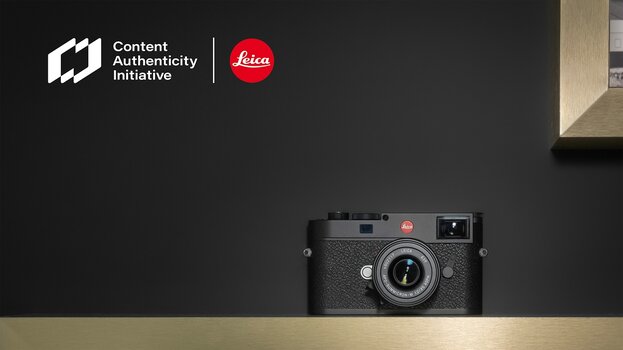 Leica-Kamera auf Holzleiste vor dunklem Hintergrund, oben Links Logos der CAI und von Leica