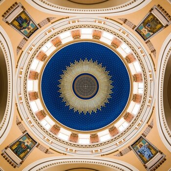 Blick von unten in die reichverzierte Kuppel einer Kirche mit geometrischen Mustern. 
