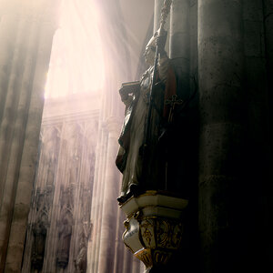 The sun is shining at a statue of a saint within the Cologne cathedral. 
The cathedral with its official name „High Cathedral of Saint Peter" is one o