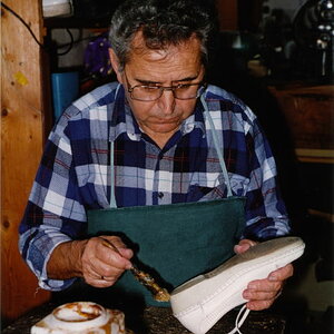 Schuhmacher beim einpinseln eines Schuhs damit ein neuer Absatz angeklebt werden kann. Ca. 1990.