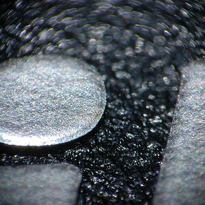 Mit selbstgebasteltem Lupenobjektiv (Maßstab 1:5,5):
Der i - Punkt der Aufschrift auf einem Nikon-Objektivdeckel
