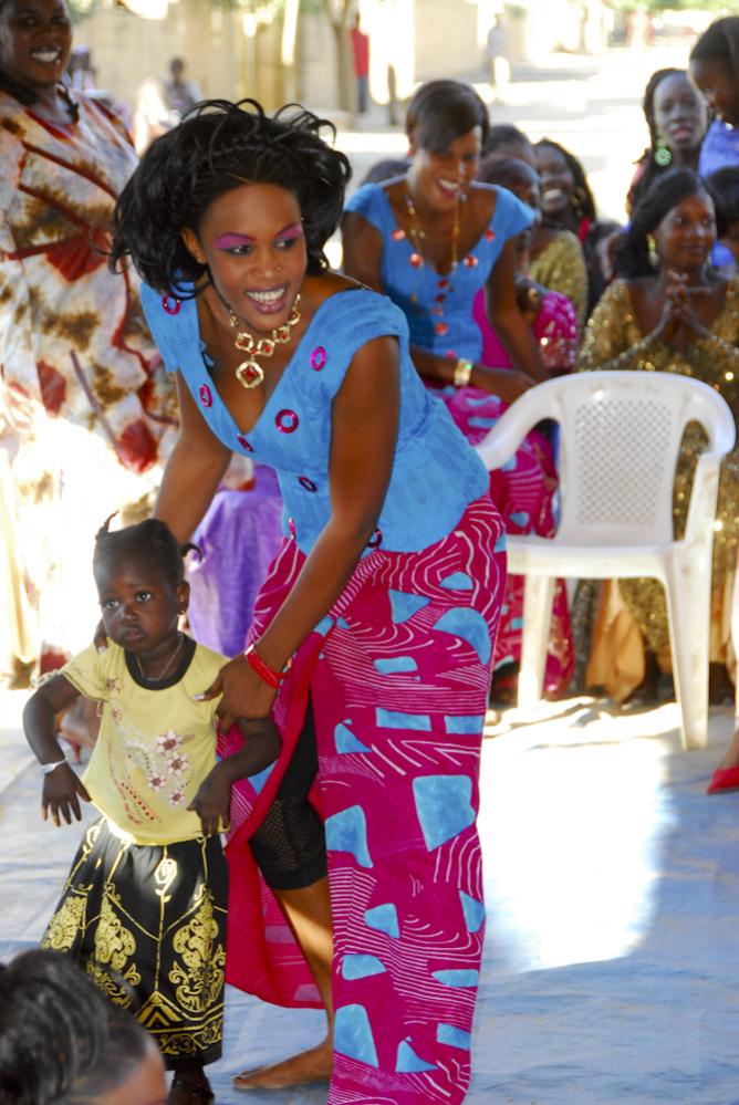 Eine der Brautjunfern mit einem Kind. Wenn im Senegal eine Frau sich intensiv um ein Kind kümmert, heißt das nicht automatisch, dass es ihr eigenes Ki