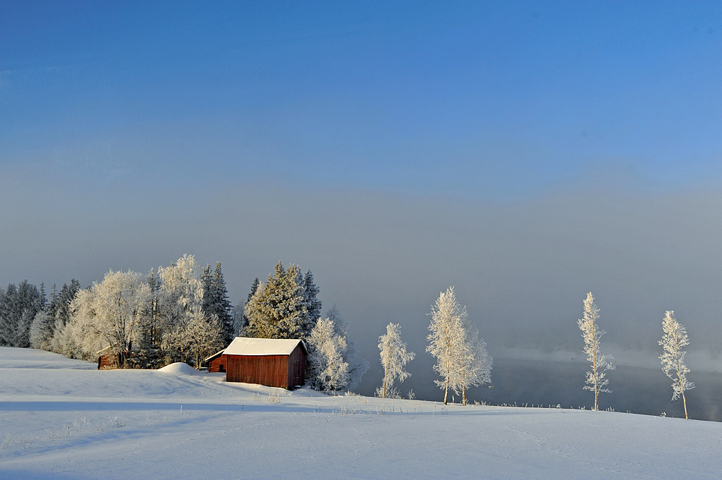 Minus 30 Grad an einem winterlichen Morgen in Schweden - das eiskalte Wasser dampft und zaubert den Nebel und den Reif zu dieser Winterlandschaft zusa