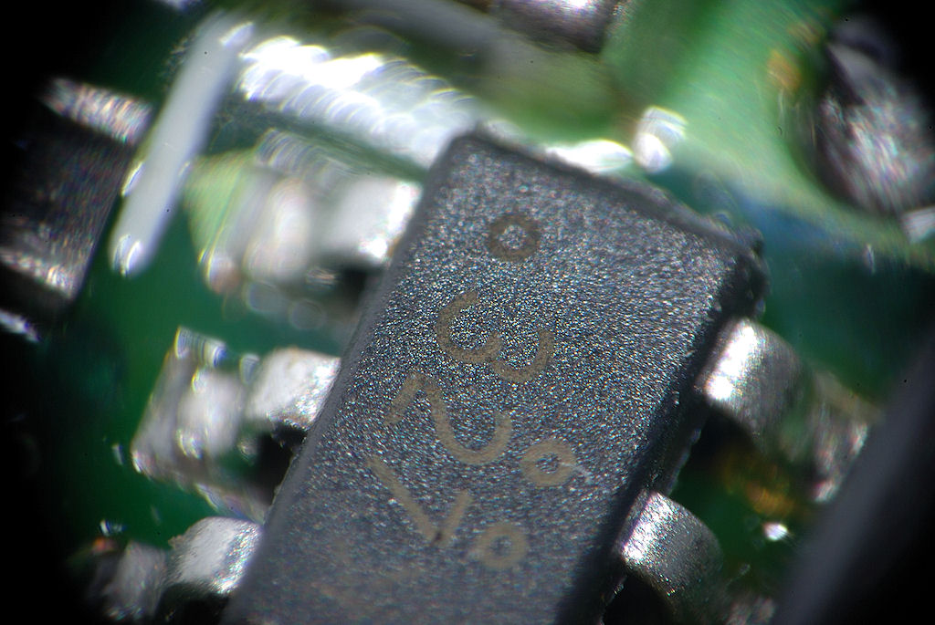 Mit selbstgebasteltem Lupenobjektiv (Maßstab 1:5,5):
Kleines IC auf einer kleinen Nikon-AF-S-Motorplatine,
Fokus auf der Beschriftung des IC