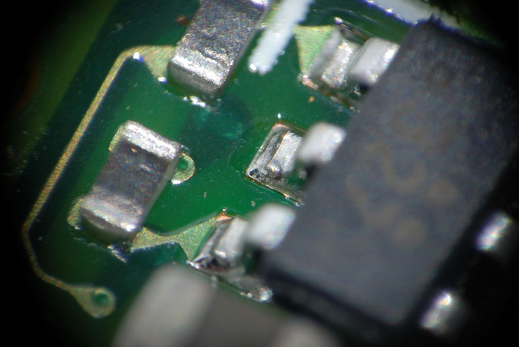 Mit selbstgebasteltem Lupenobjektiv (Maßstab 1:5):
Kleines IC auf einer kleinen Nikon-AF-S-Motorplatine,
Fokus auf den Füßen des IC