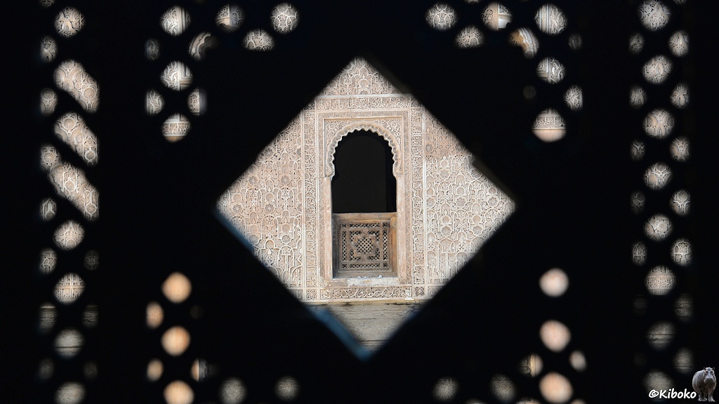 Blick durch eine Rautenförmige Öffnung auf ein Fenster mit orientalischen Mustern.