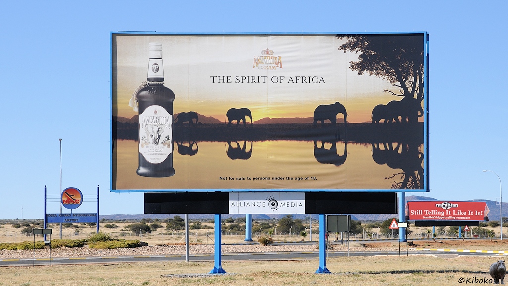Auf einem Werbeplakat laufen Elefanten im Sonnenuntergang und spiegeln sich im Wasser.