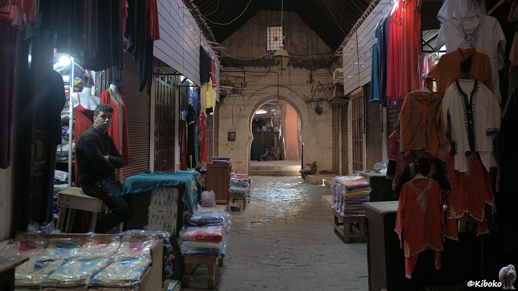 Ein Verkäufer sitzt vor seinem Bekleidungsgschäft in der nächtlichen Gasse im Souk