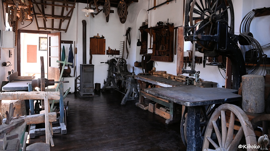 Das Bild zeigt die Innenansicht der Werkstatt eines Wagenbauers. In der Werkstatt stehen Maschinen zur Herstellung hölzerner Wagenräder.
