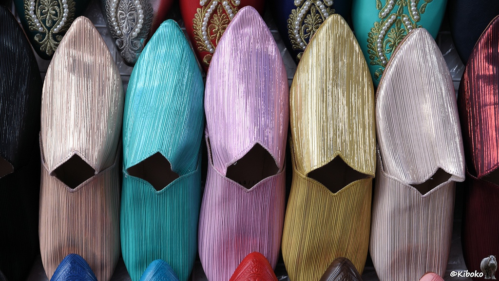 Das Bild zeigt fünf bunte Hausschuhpare mit Glanzstreifen in silber, türkis, lila, gold und weiß.