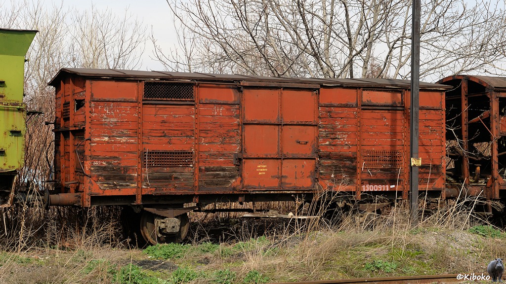 Das Bild zeigt einen rotbraunen Holzgiüterwagen mit Spitzdach und Blechtür auf einem Abstellgleis.