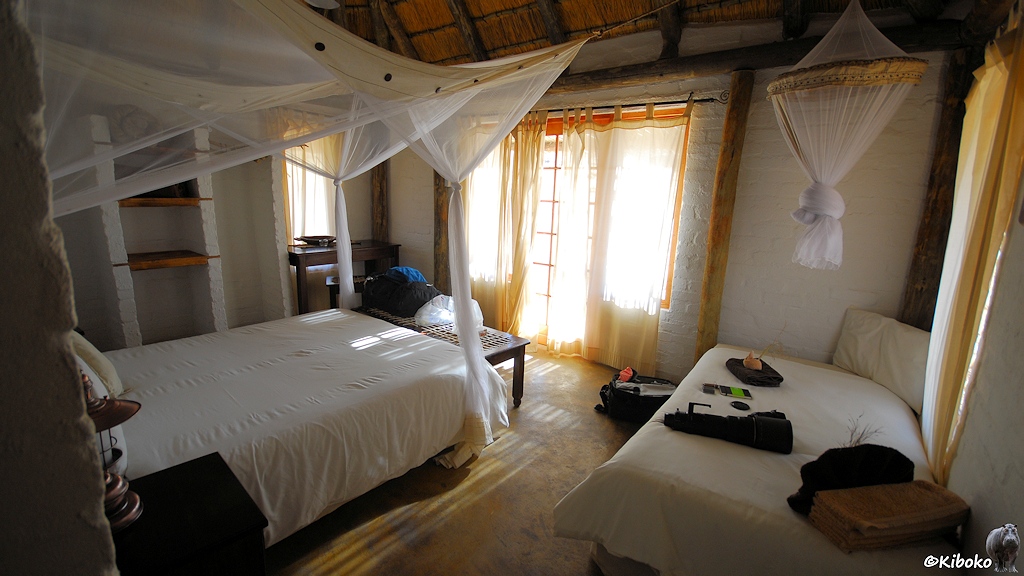 Innenansicht der Hütte mit Blick zur Eingangstür. Ein Doppelbett und ein Einzelbett sind durch Moskitonetze geschützt.
