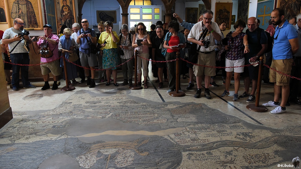 Mensten hinter der Absperrung am Mosaik mit der Palästinakarte