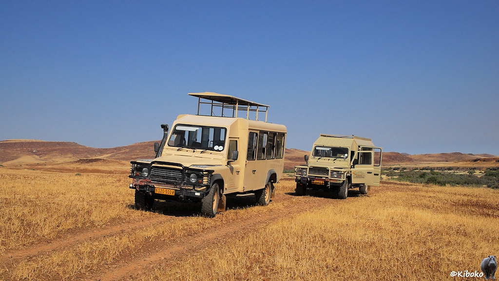 Zwei Geländewagen auf einem mit gras bewachsenen Hügel.
