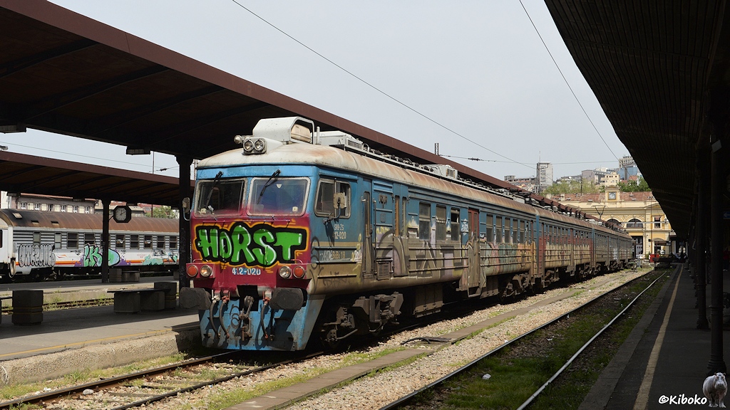 Das Bild zeigt einen kantigen, vierteiligen Elektrotriebwagen am Bahnsteig. Der Zug ist mit Grafitti verschmiert. An der Front steht mit großen grünen Buchstaben: Horst.