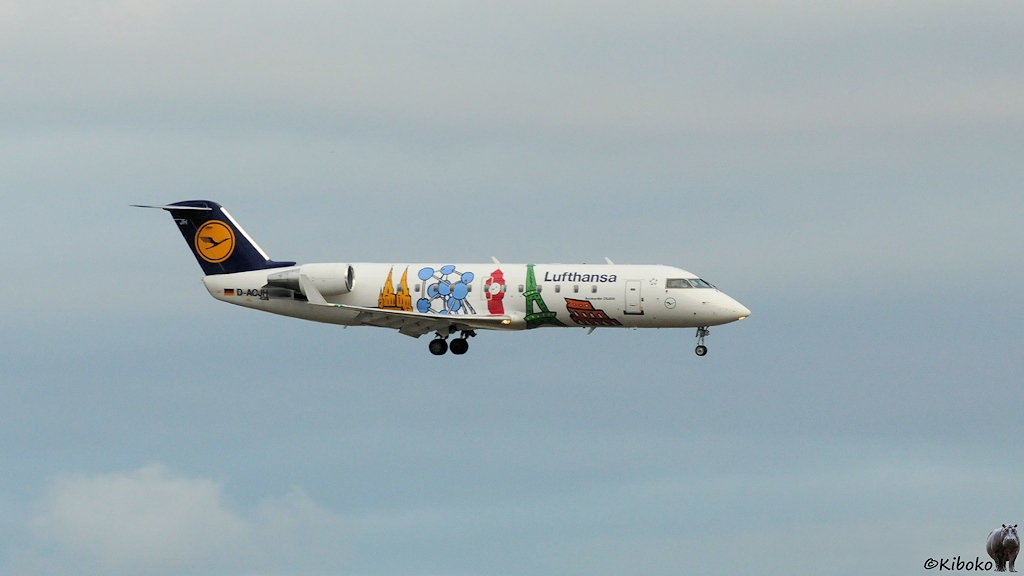 Kleiner Lufthansa Jet beim Landeanflug mit aufgemaltem Kölner Dom, Atomium, Eifelturm, Big Ben und Kolosseum