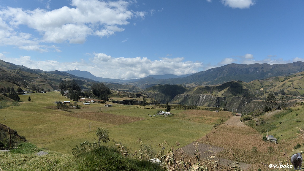 Das Bild zeigt zeigt einen Talboden mit Feldern. Im Hintergrund ist eine weitläufige Berglandschaft.